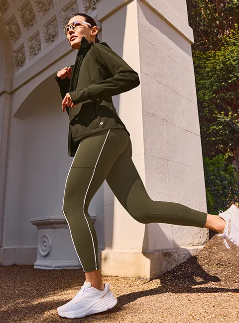 Vrouw rent buiten in donkergroene Sweaty Betty Power legging.