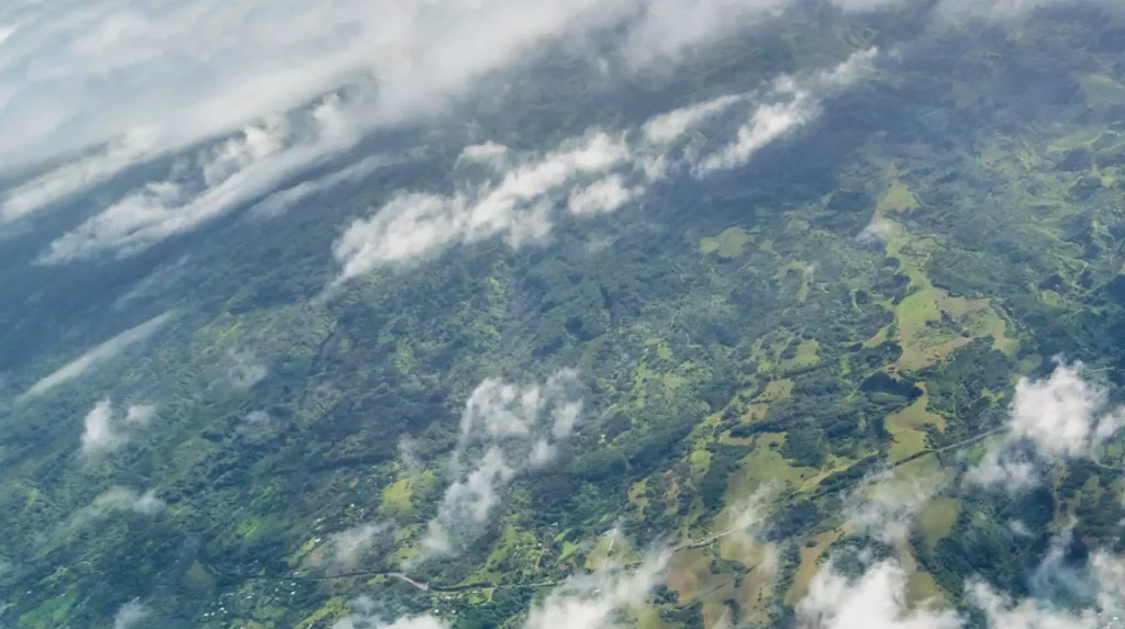 Luchtfoto van groen landschap met wolken boven het dal.